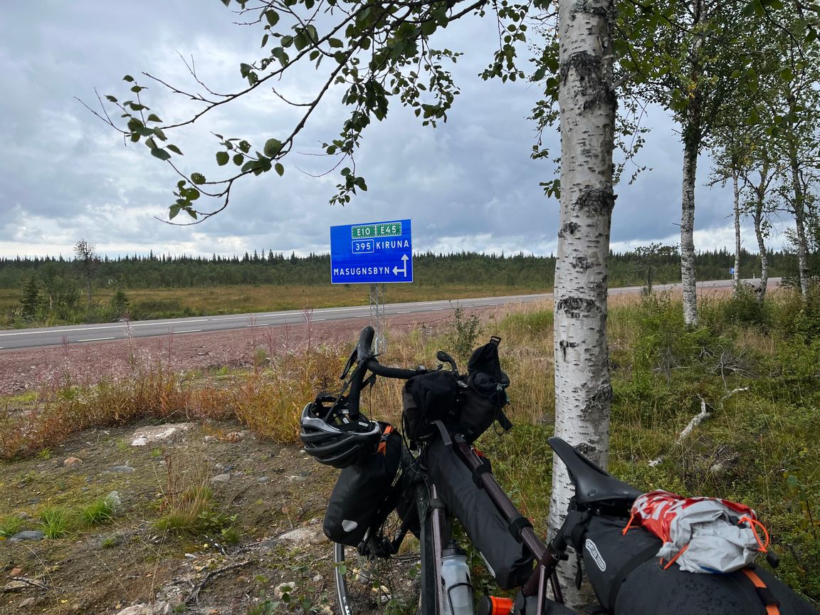 My bike on the foreground with a street sign with directions to Kiruna in the background