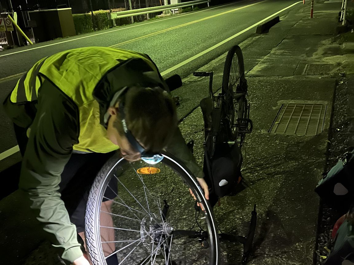 Oskar fixing a broken tire on the curb in the dark