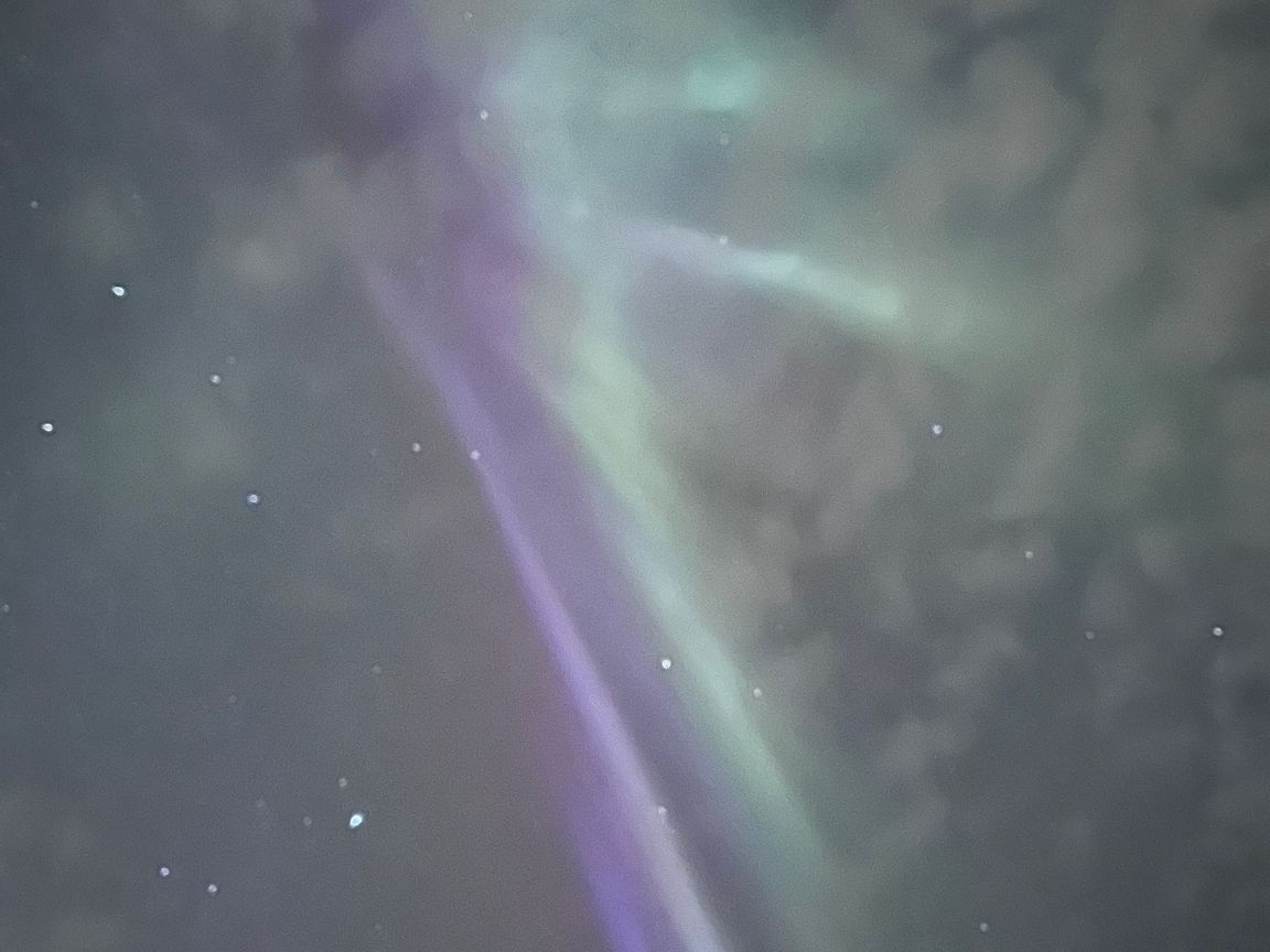 Faint green and purple aurora with some clouds