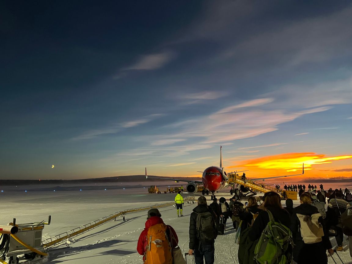 Norwegian plane boarding people with noctilucent clouds in the background