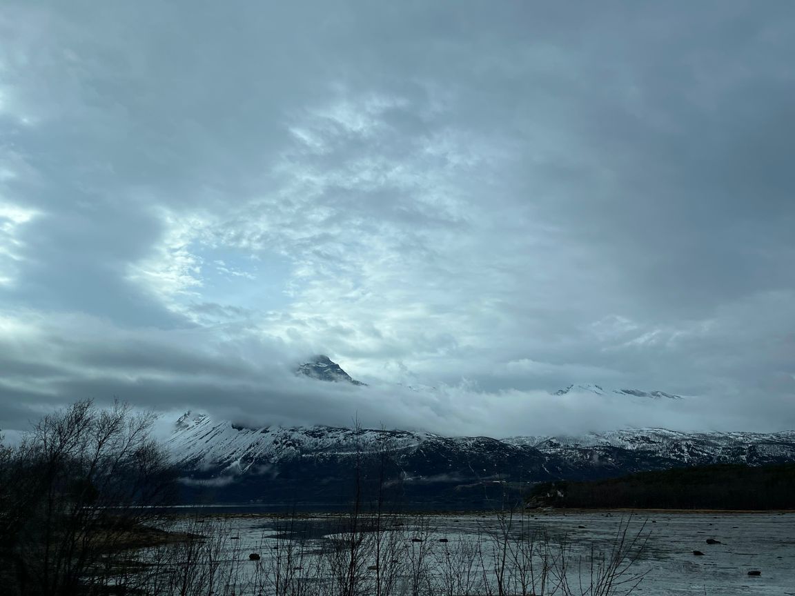 Mountain near Narvik surrounded by clouds, with the fjord on the foreground